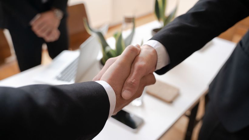 Close-up of a handshake between two professionals in a business setting, symbolizing agreement