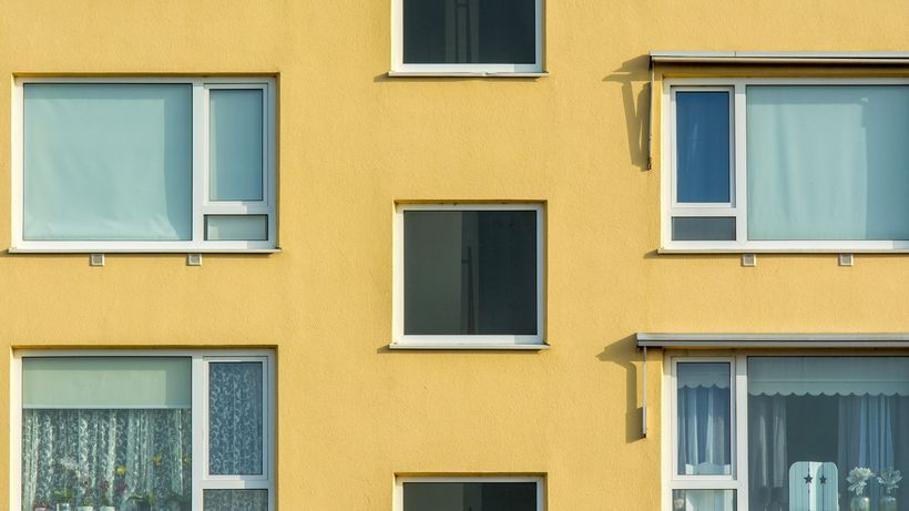 Close-up view of a yellow apartment building facade with windows and balconies