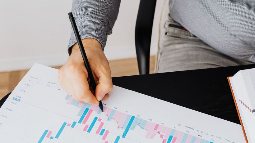 Detailed financial graph showing analysis by a person with a pen indoors
