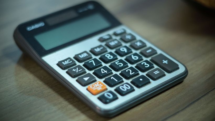 Digital calculator resting on a wooden table, selective focus
