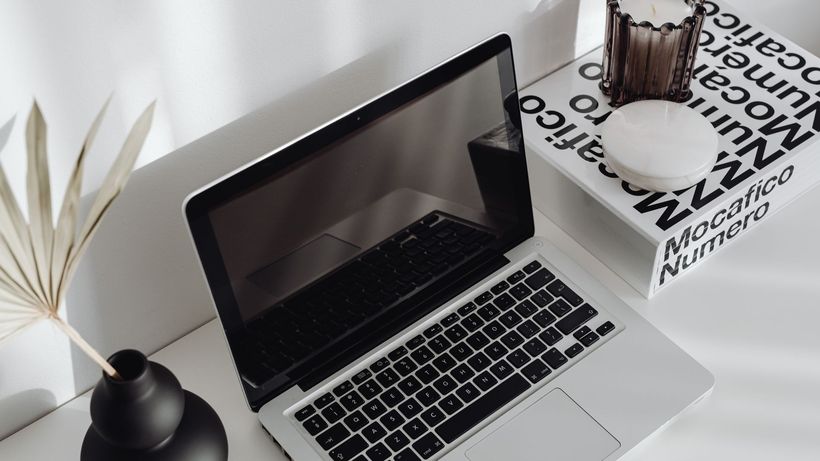Stylish minimalist desk setup with a laptop and decorative items in bright lighting