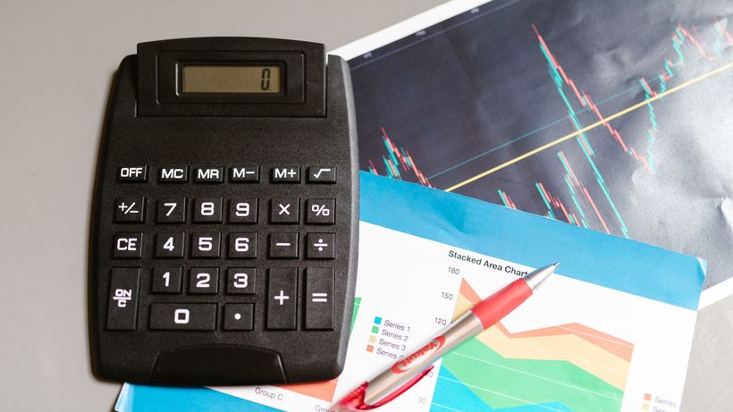 Calculator and pen on a desk with financial charts, showcasing analysis and business planning