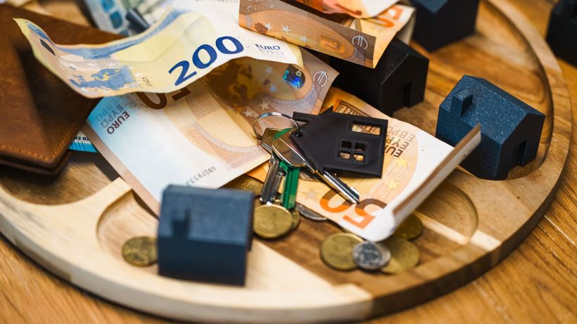 Euro currency, keys, and miniature houses symbolize real estate and finance concepts