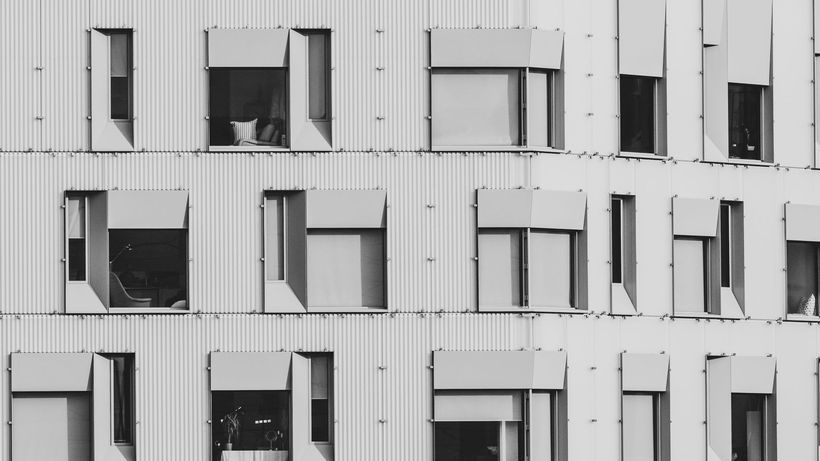 Black and white image of a modern building facade with rectangular windows and shutters