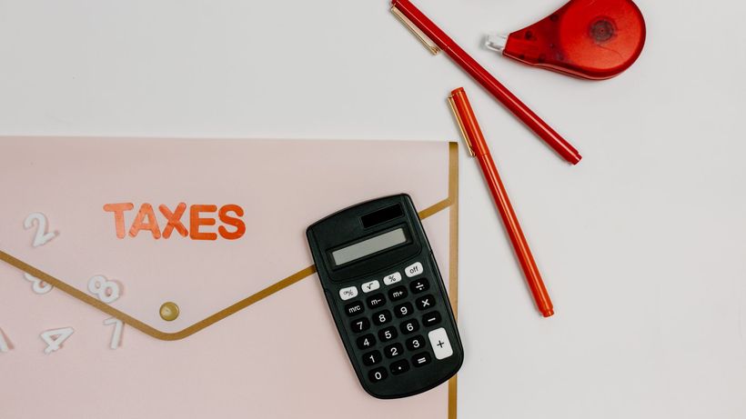 Flat lay image featuring a calculator, pens, and a folder labeled 'TAXES', perfect for finance-related themes
