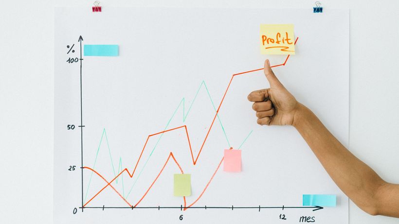 A hand giving thumbs up next to profit chart on a whiteboard, indicating success