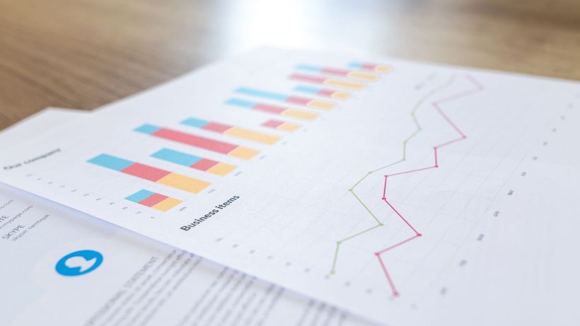 A close-up view of a business document with charts and graphs on a wooden desk