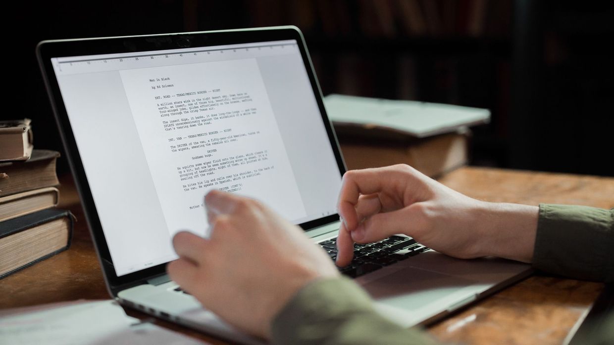 SEO versus content marketing: a person typing on a laptop in a cozy workspace with books around. Perfect for writing