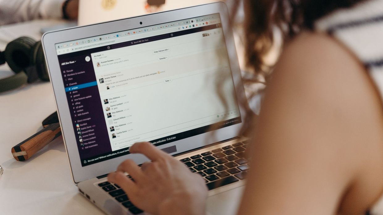 SEO versus email marketing: a businesswoman typing on a laptop in an office setting, using Slack for communication