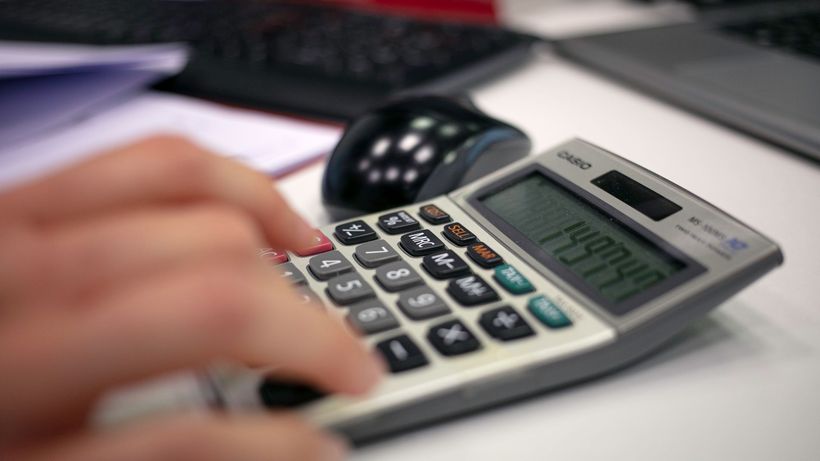Close-up of a hand using a calculator on an office desk for accurate calculations