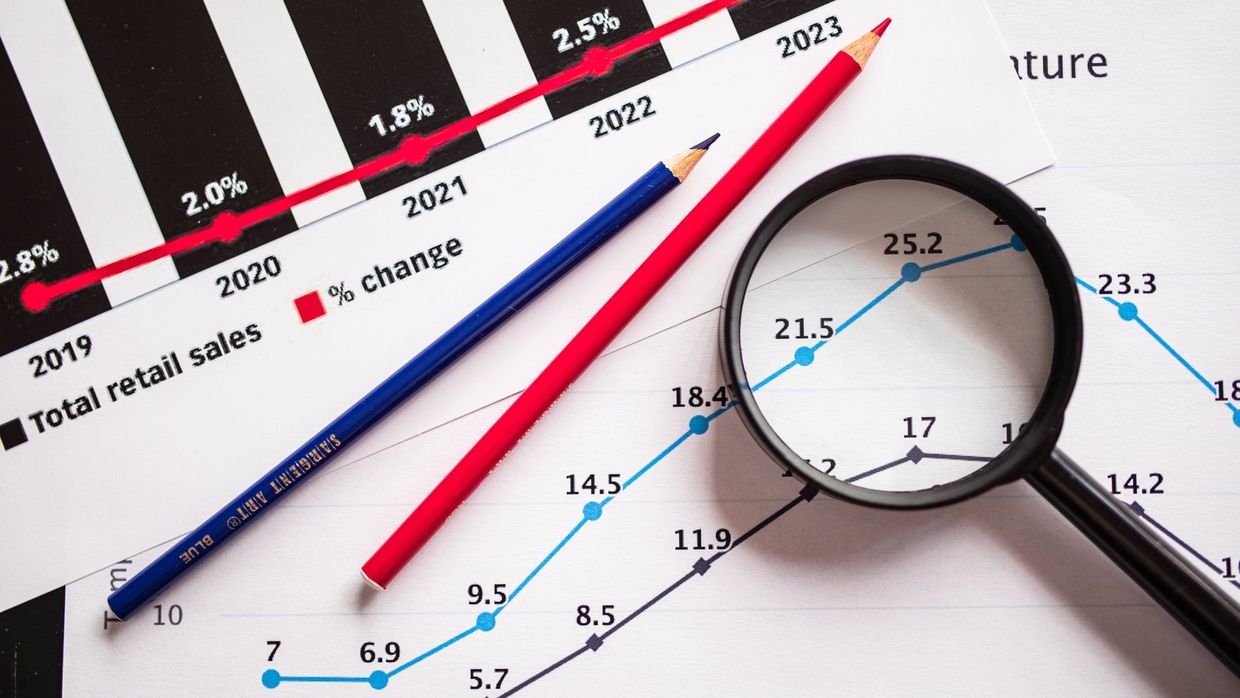 Share of voice: magnifying glass and colored pencils on financial trend graphs highlighting sales growth