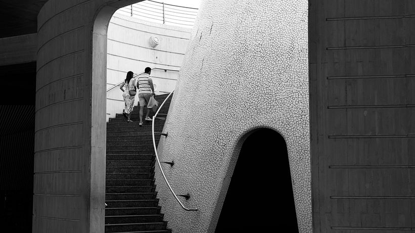 Black and white photo of a couple ascending a modern architectural staircase
