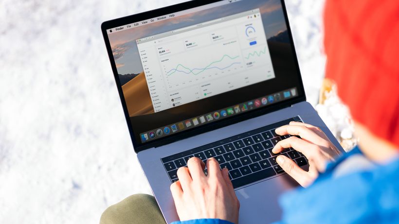 A person in a blue jacket analyzing business analytics on a laptop outdoors during winter
